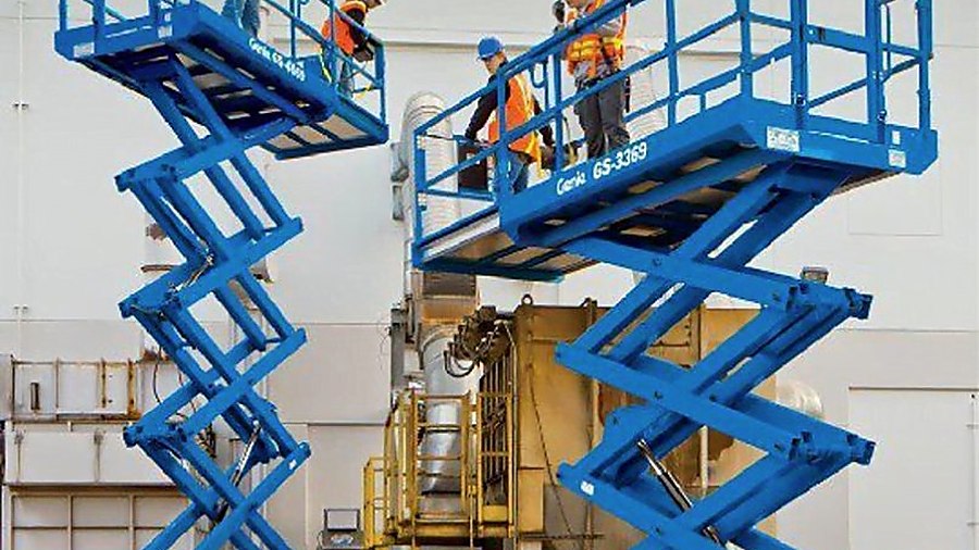 hai scissor lift genie gs đang làm việc ngoài nhà xưởng công nghiệp